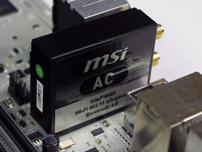 A photo of a small black box vertically attached to the back of the motherboard labeled MSI AC Intel WiDi Wi-Fi 802.11 a/b/g/n/a... Bluetooth 4.0.