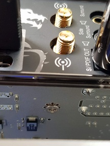 A photo from underneeth of the motherboard shoting a screw and no through-the-hole soldering joints of any kind. Part of the backplate with anntena connectors is also visible right above where the screw is.